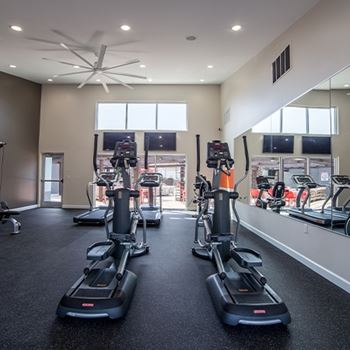 A gym with treadmilers and elliptical machines.